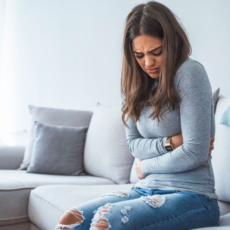 Unhappy beautiful woman suffering from stomach ache at home